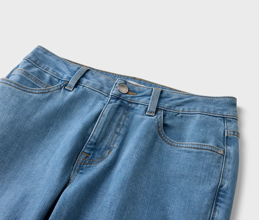 Nahaufnahme einer hellblauen Jeans mit Taschen, Gürtelschlaufen und einem silberfarbenen Knopf.