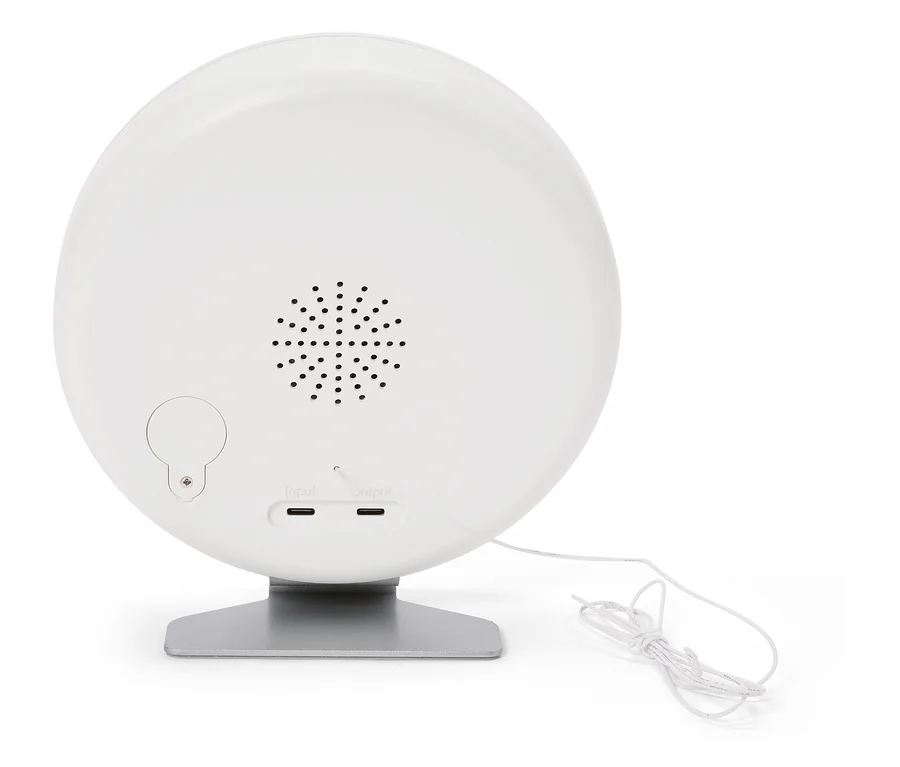 Rückseite einer runden, weißen Lampe auf einem silbernen Sockel mit Lautsprecher, Eingangs- und Ausgangsanschlüssen und einem weißen Kabel.