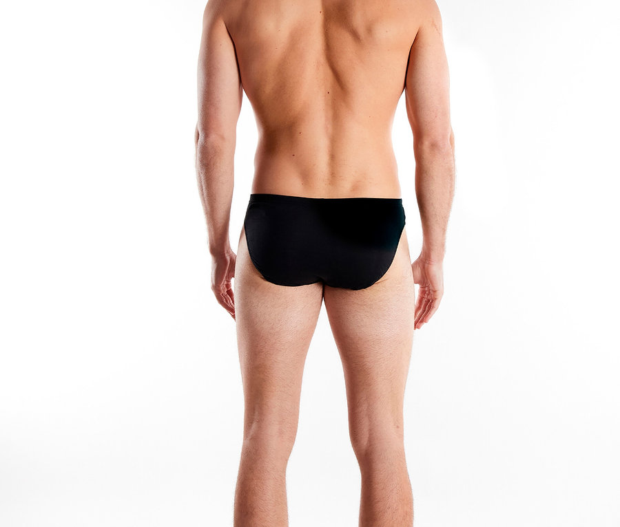 Mann von hinten, mit schwarzer Badehose vor einem weißen Hintergrund.