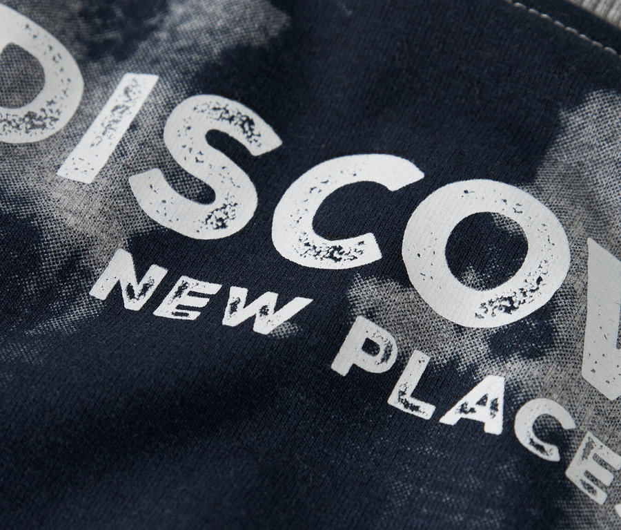 Nahaufnahme eines dunkelblauen Stoffes mit dem Aufdruck "DISCOVER NEW PLACES".