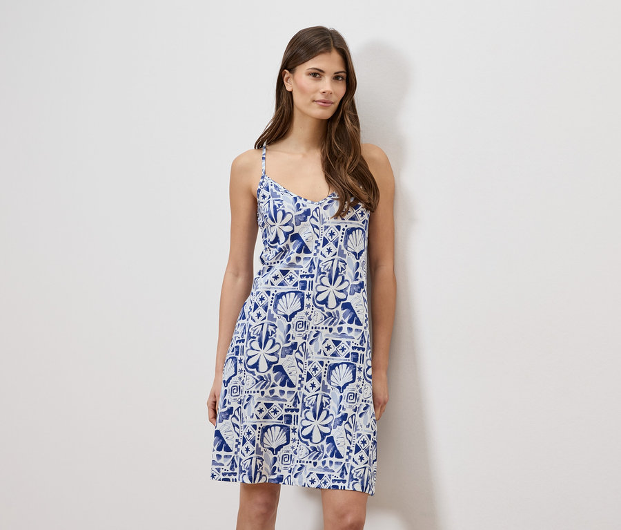 Frau trägt ein blau-weißes, ärmelloses Sommerkleid.