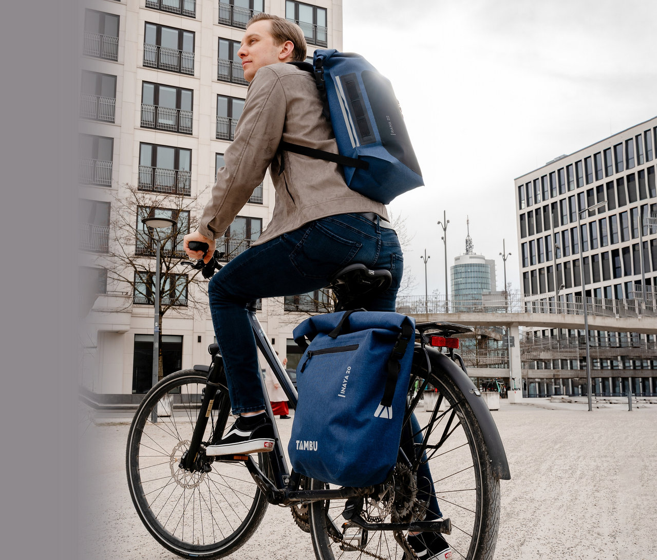 Mann fährt mit einem Fahrrad mit einer blauen Tambu »INAYA« Fahrradtasche.