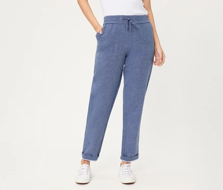Eine Person trägt eine blaue Olsen Cropped Jeans mit Kordelzug, aufgesetzten Taschen und umgekrempelten Säumen, dazu weiße Sneaker.