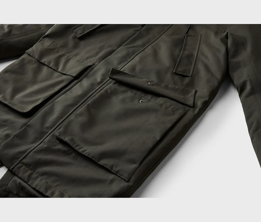 Nahaufnahme einer dunkelgrünen Jacke mit mehreren Pattentaschen, einige davon mit Druckknöpfen.