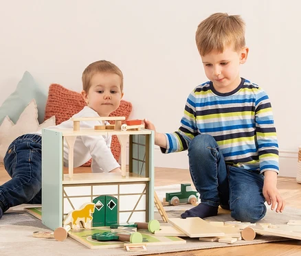 Zwei Jungen spielen mit dem Pinolino Spielwelt »Reiterhof Lise« aus Holz.