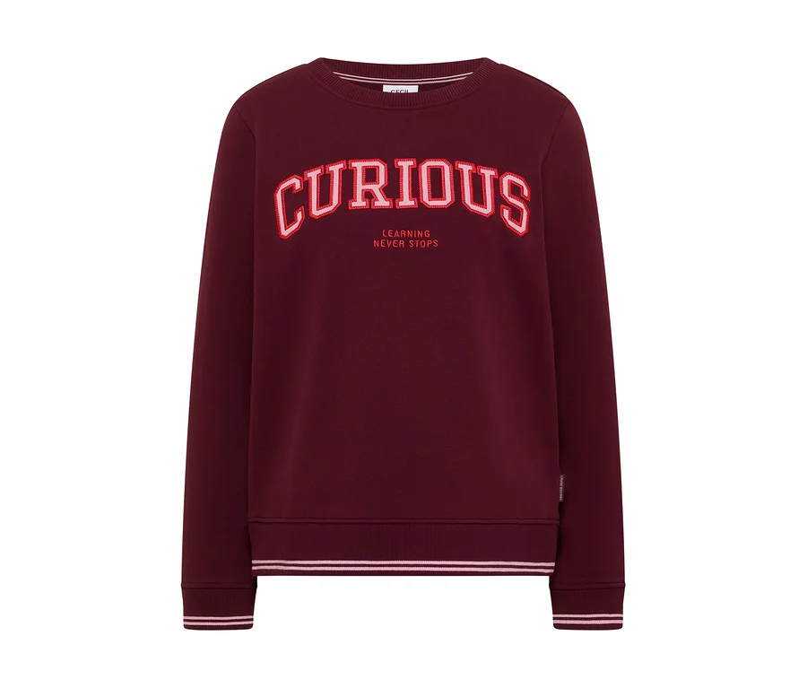 Bordeauxrotes CECIL Sweatshirt mit dem roten Schriftzug „CURIOUS“ und „LEARNING NEVER STOPS“ auf der Brust.
